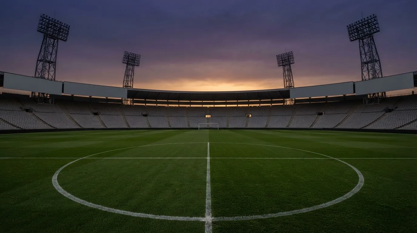 An empty football stadium with floodlight masts at dusk