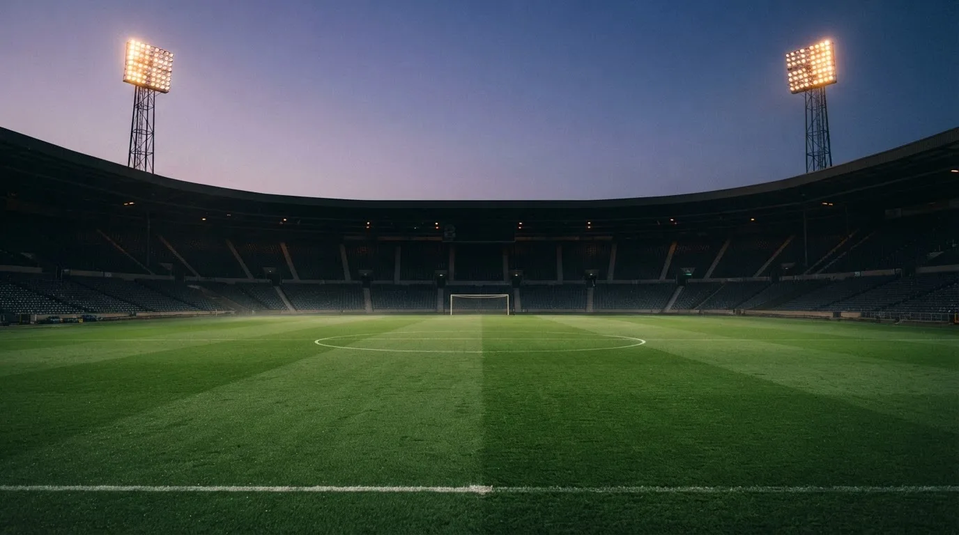 An empty football stadium with floodlight masts at dusk