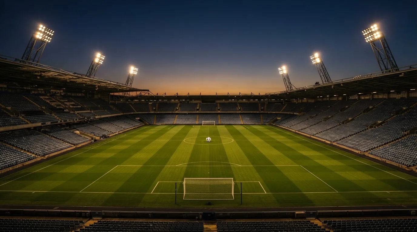 An empty football stadium with floodlight masts at dusk