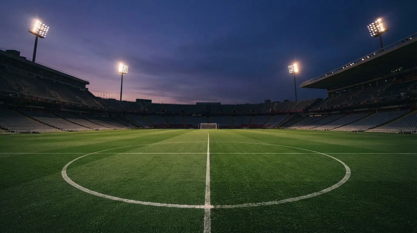 An empty football stadium with floodlight masts at dusk