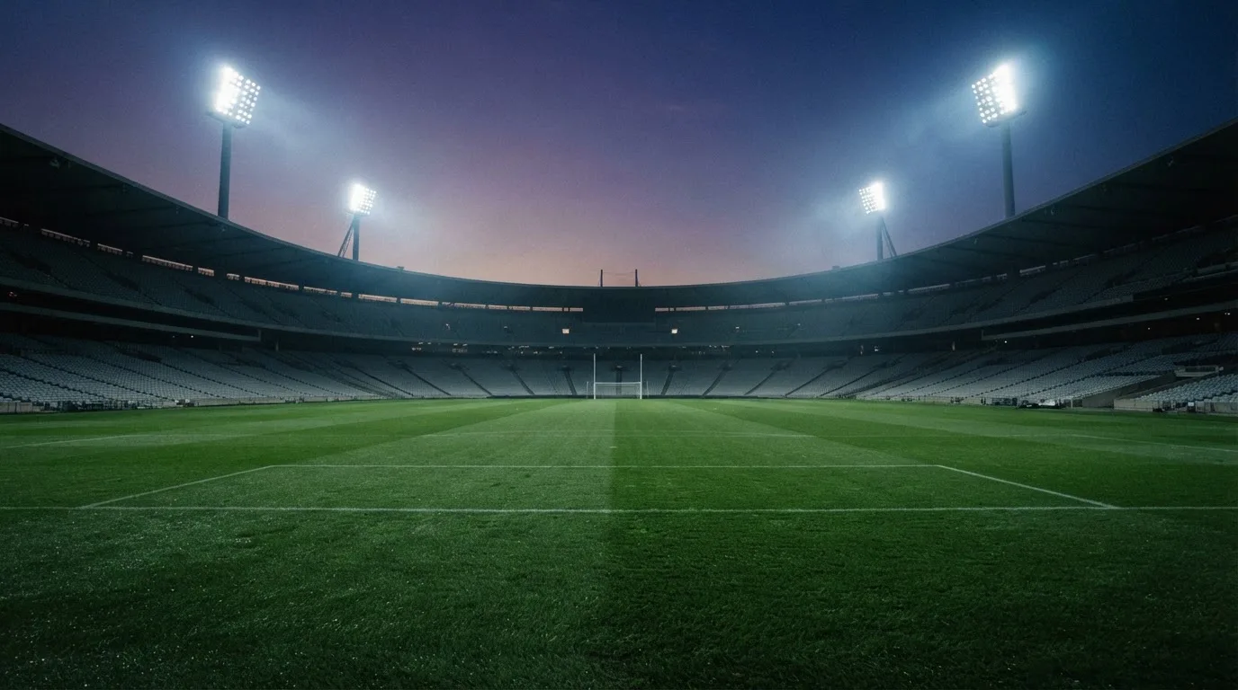 An empty football stadium with floodlight masts at dusk