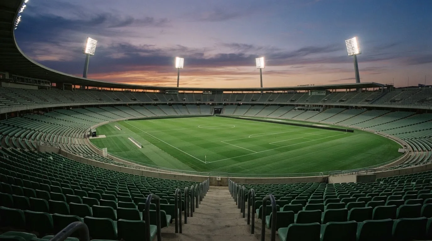 An empty football stadium with floodlight masts at dusk