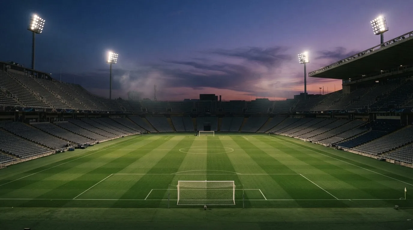 An empty football stadium with floodlight masts at dusk