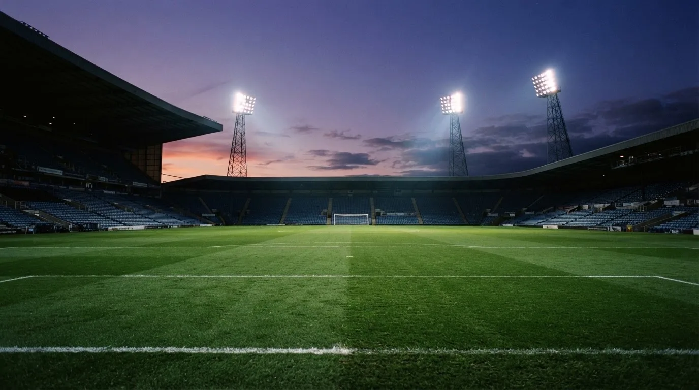 An empty football stadium with floodlight masts at dusk