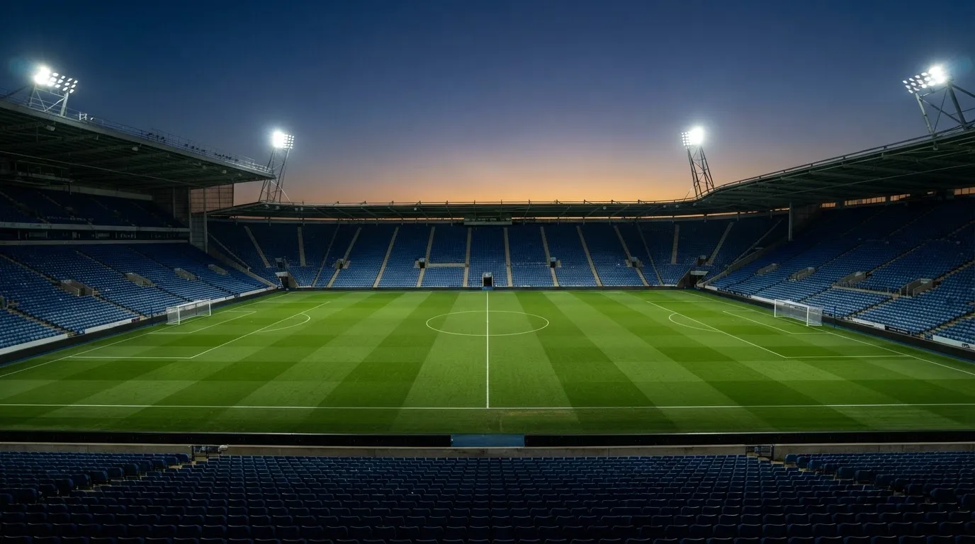 An empty football stadium with floodlight masts at dusk