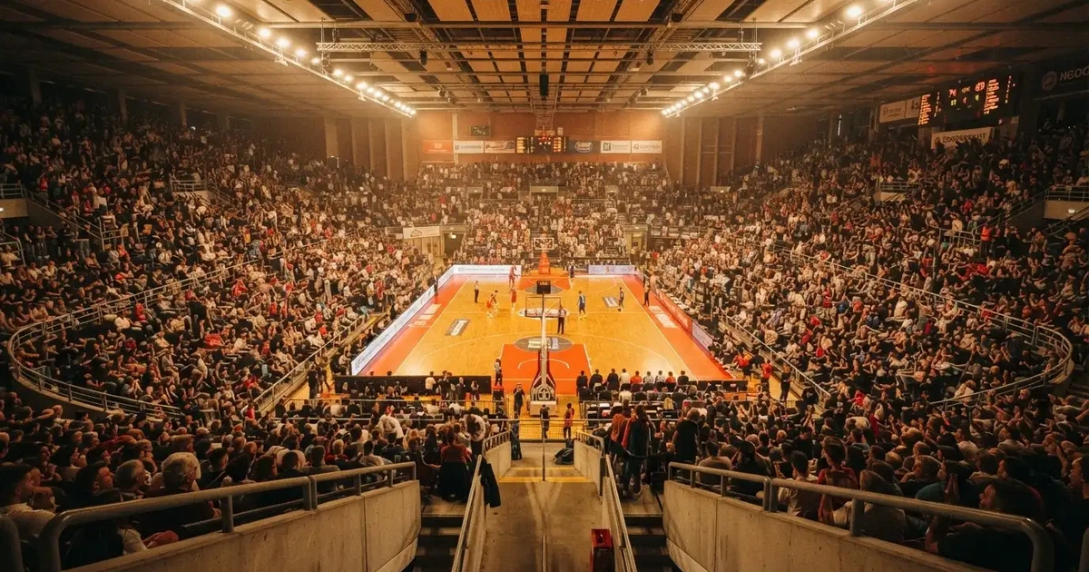 A packed sports hall under floodlights photographed from a long way off