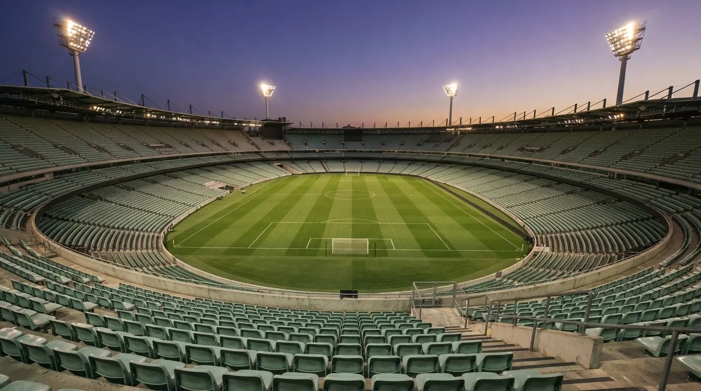 An empty football stadium with floodlight masts at dusk