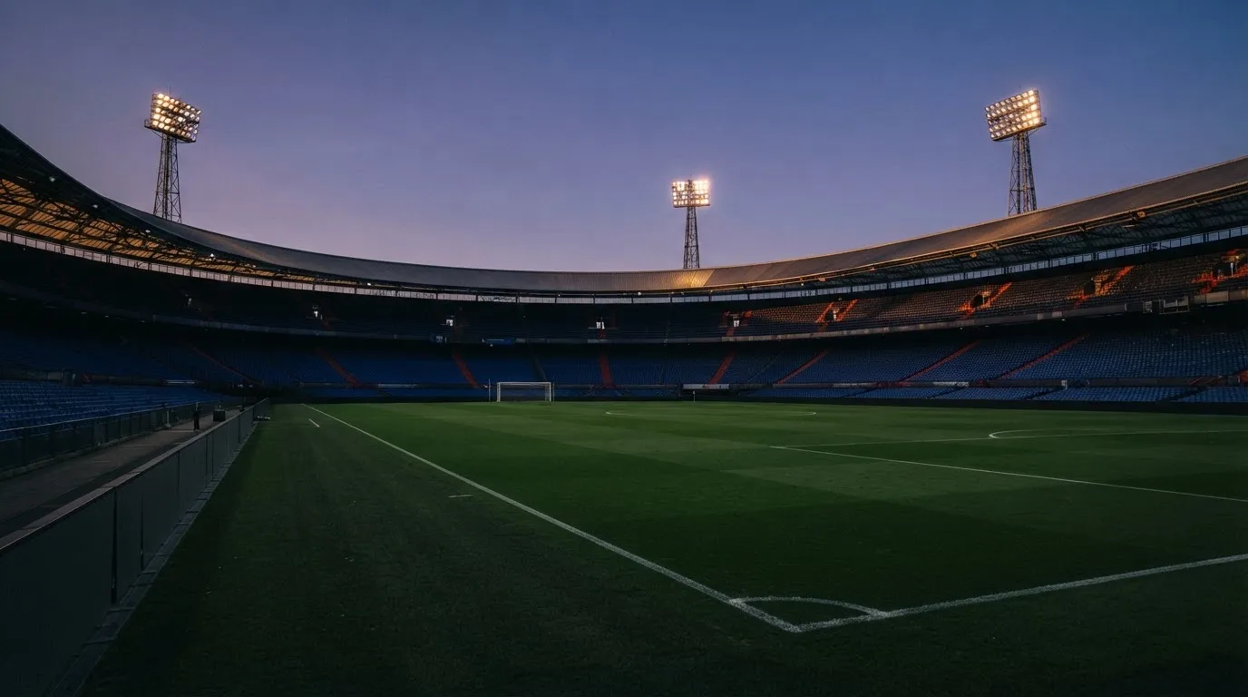 An empty football stadium with floodlight masts at dusk
