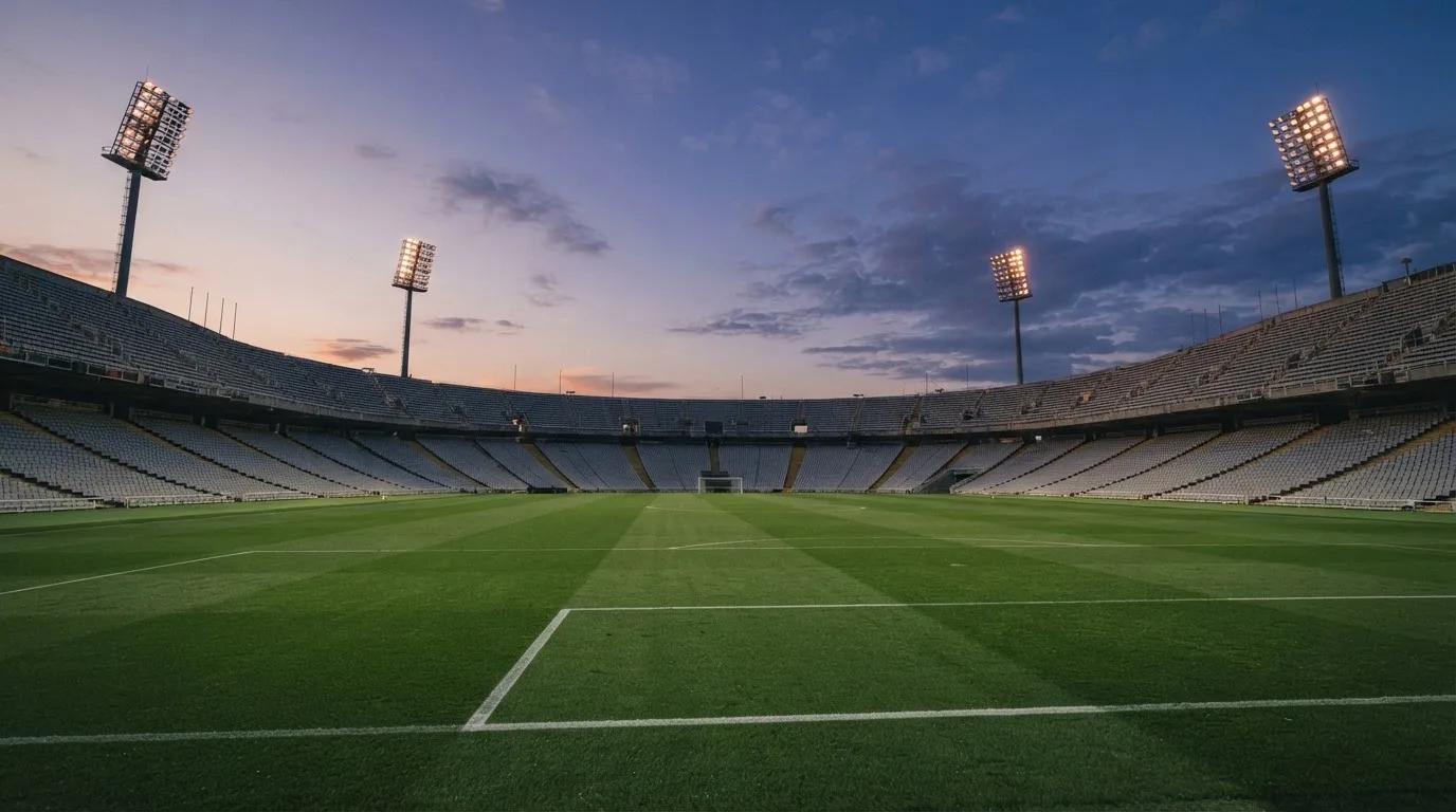 An empty football stadium with floodlight masts at dusk