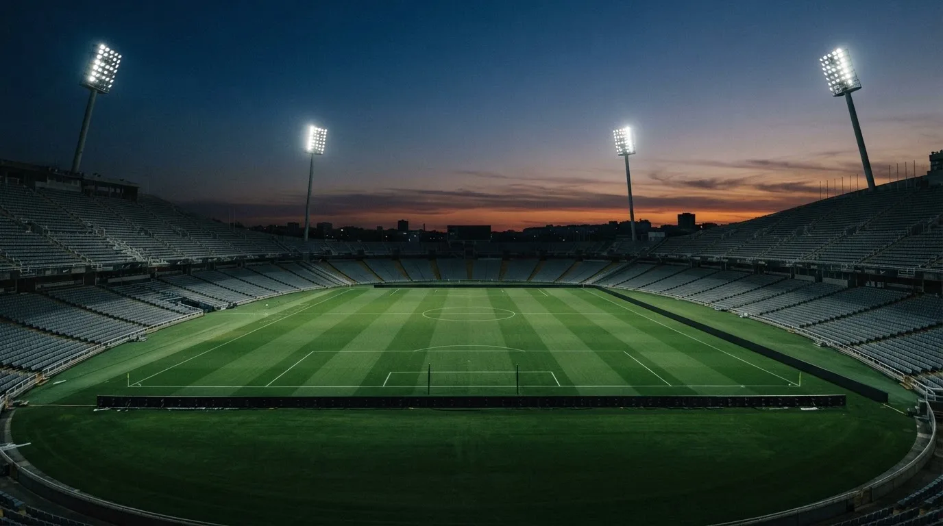 An empty football stadium with floodlight masts at dusk