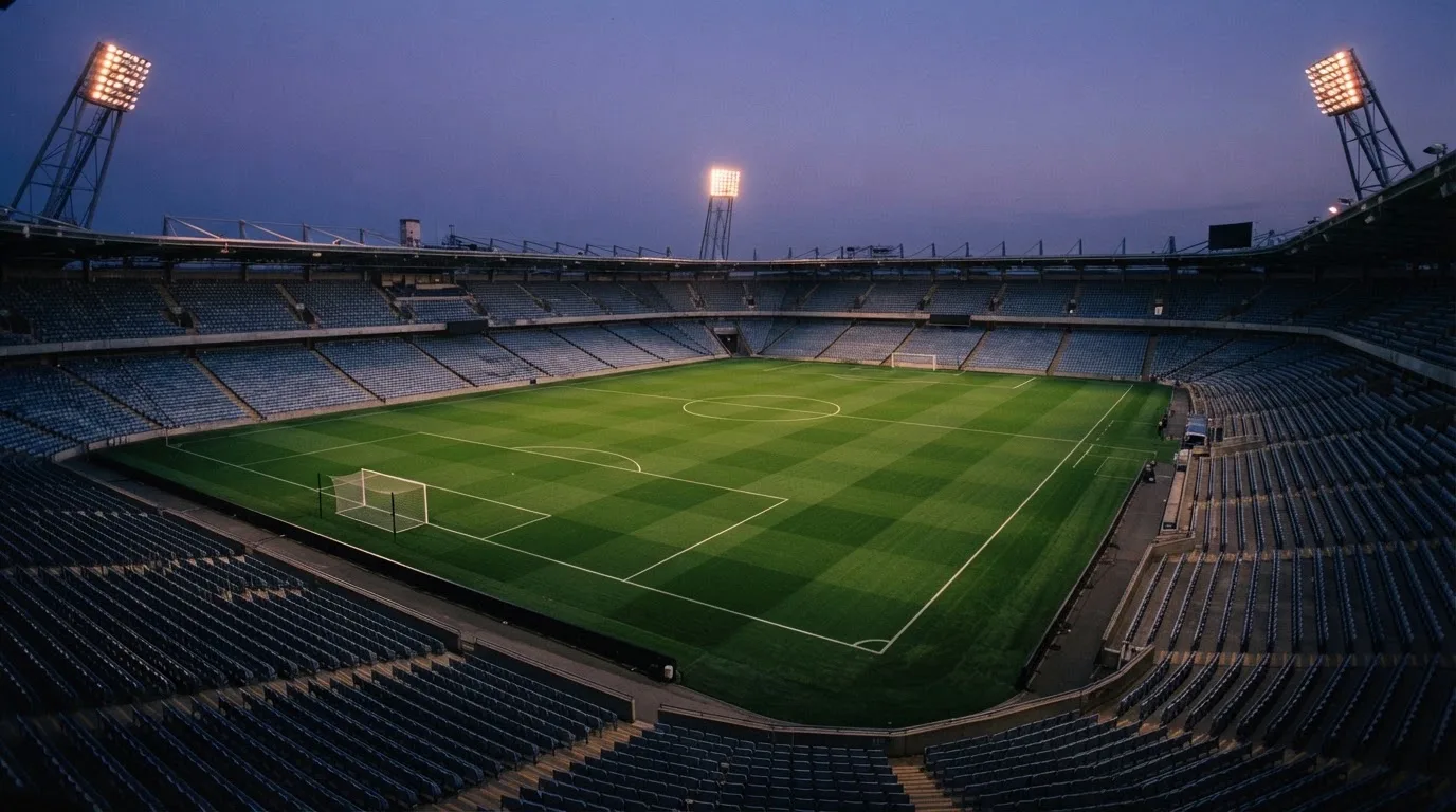 An empty football stadium with floodlight masts at dusk