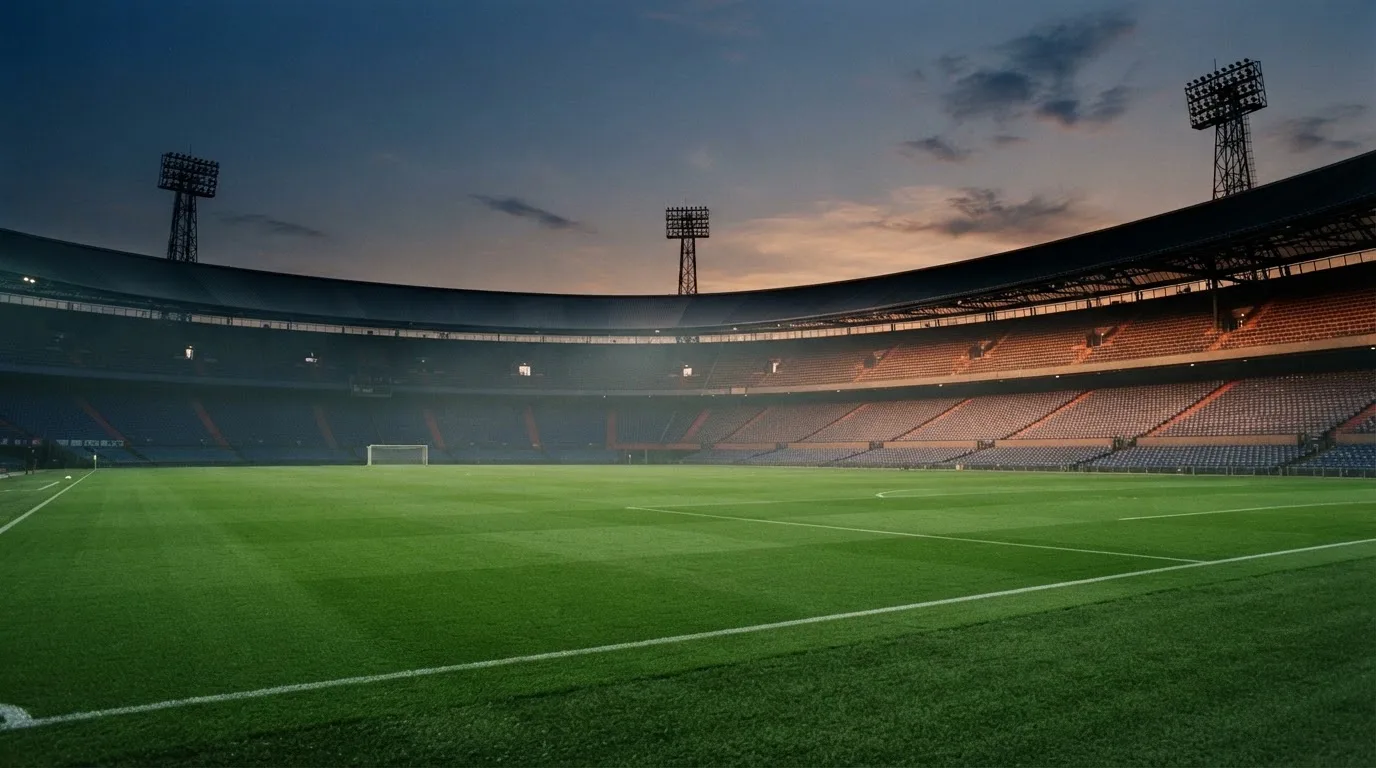An empty football stadium with floodlight masts at dusk