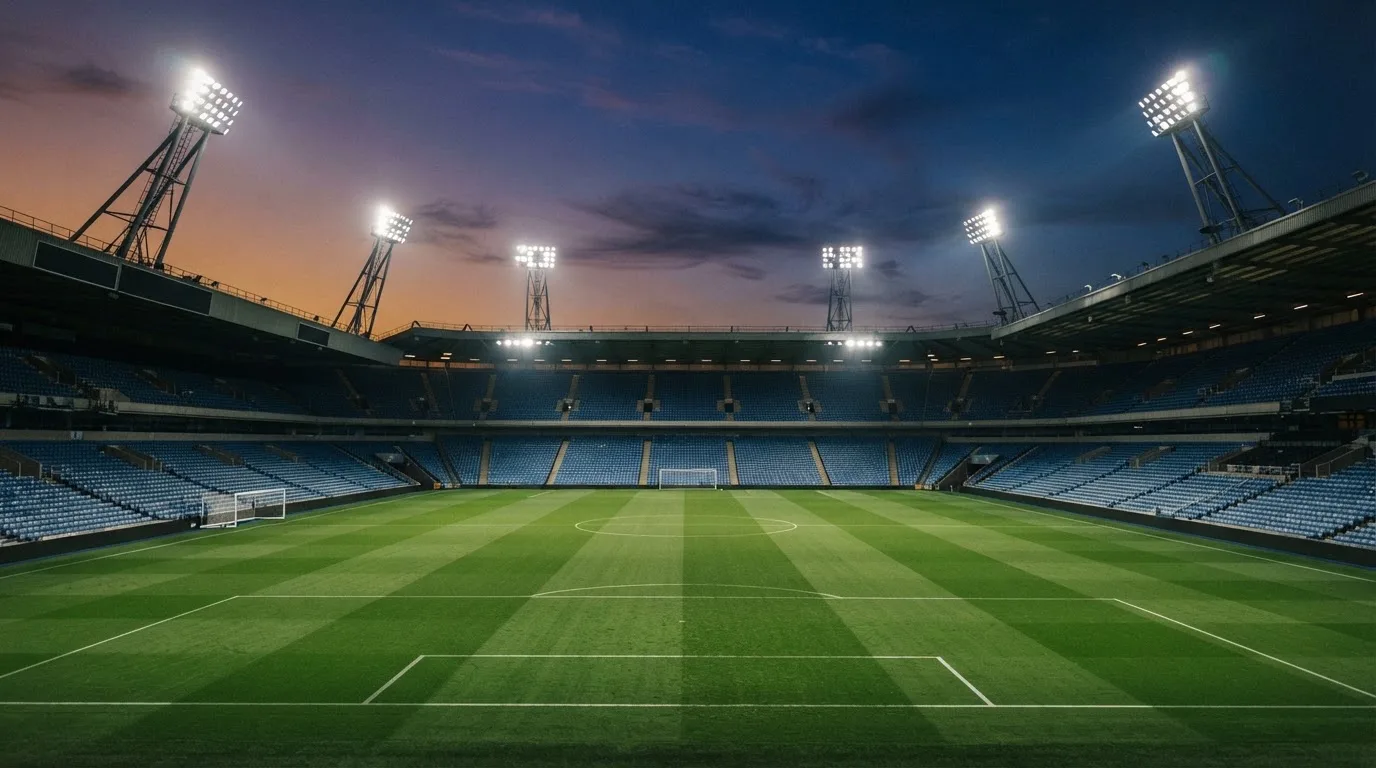 An empty football stadium with floodlight masts at dusk