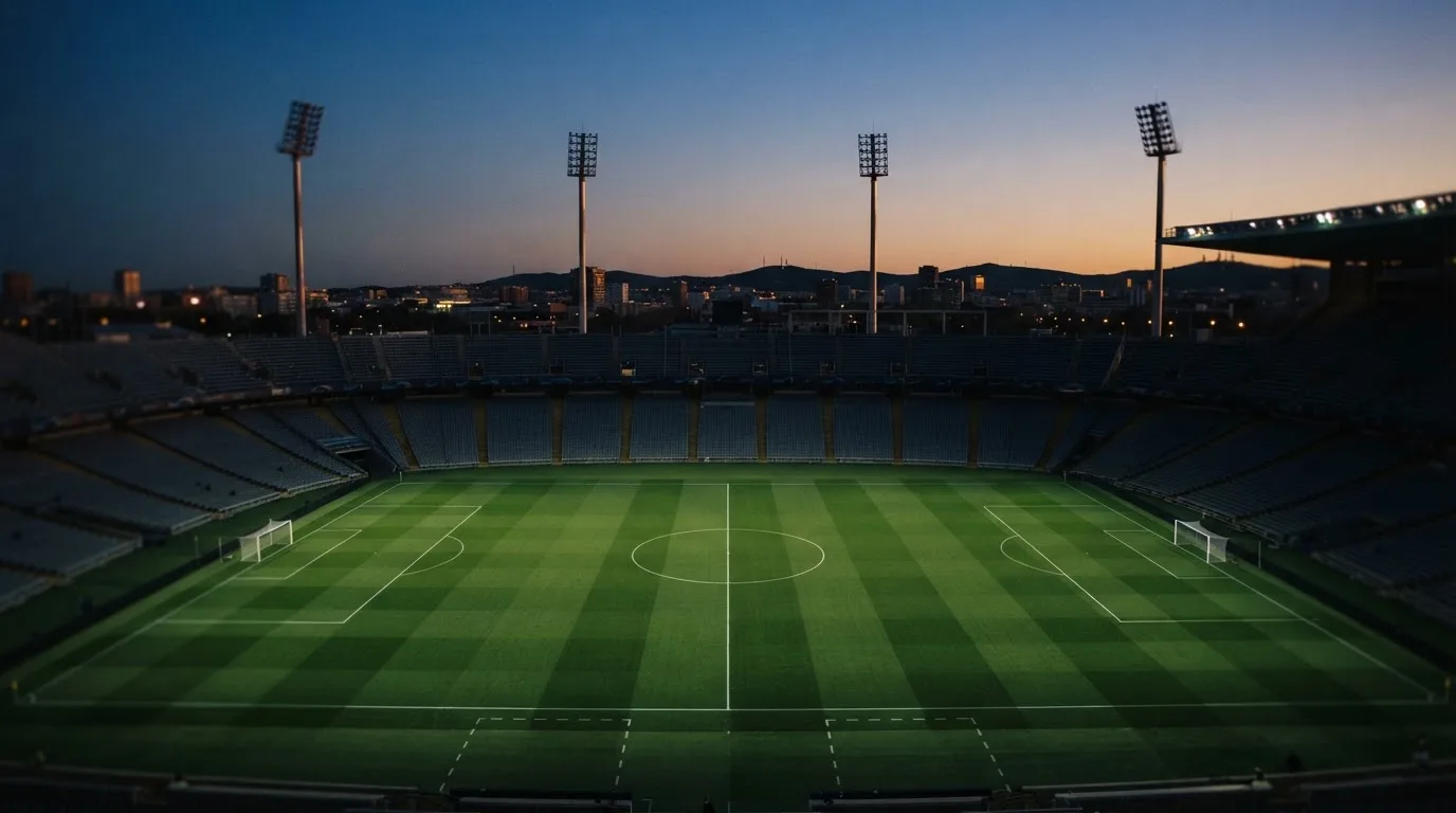 An empty football stadium with floodlight masts at dusk