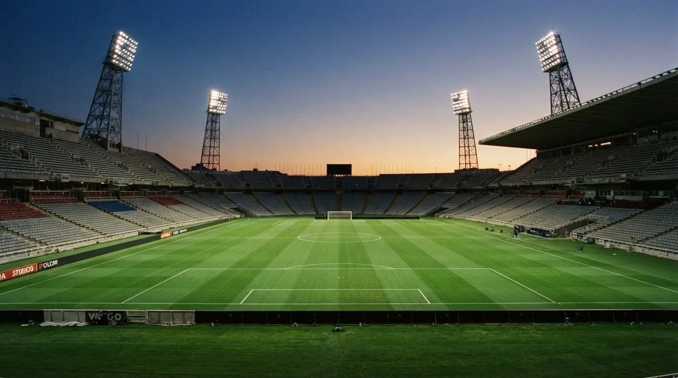 An empty football stadium with floodlight masts at dusk
