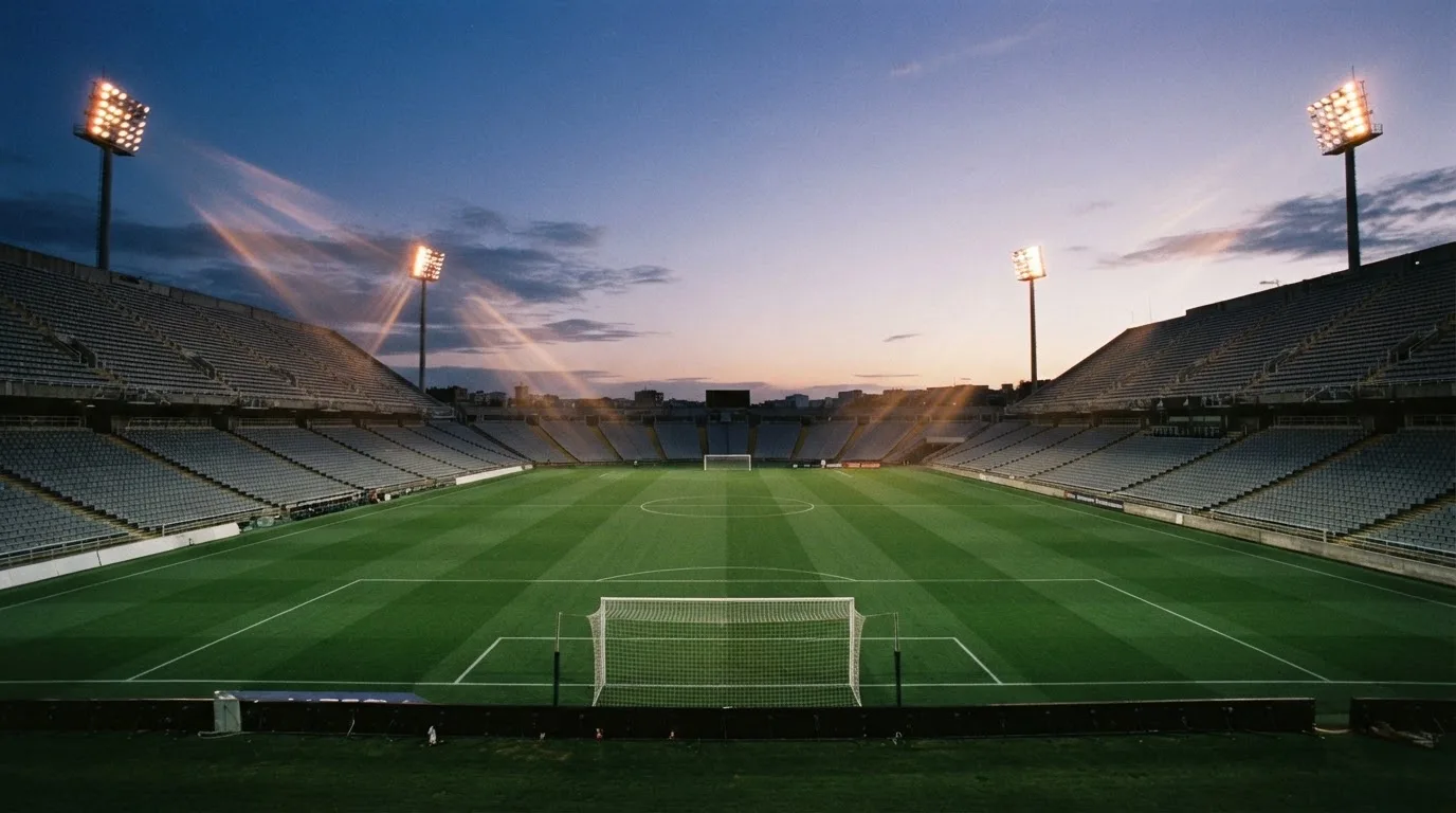 An empty football stadium with floodlight masts at dusk