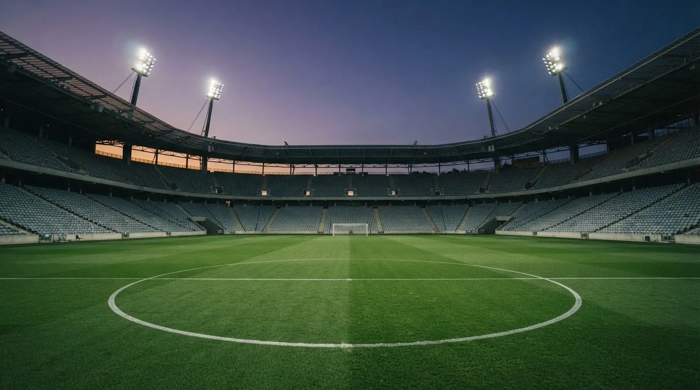 An empty football stadium with floodlight masts at dusk