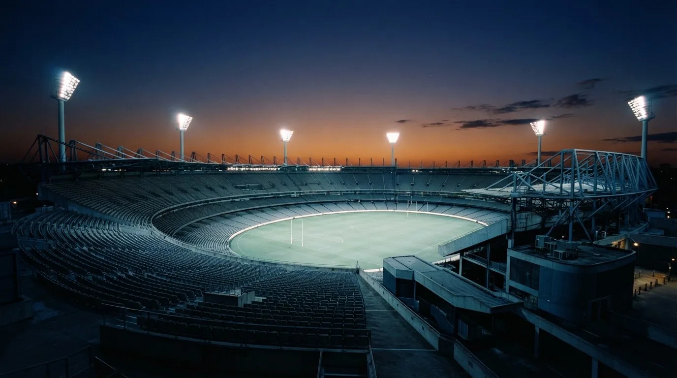 An empty football stadium with floodlight masts at dusk