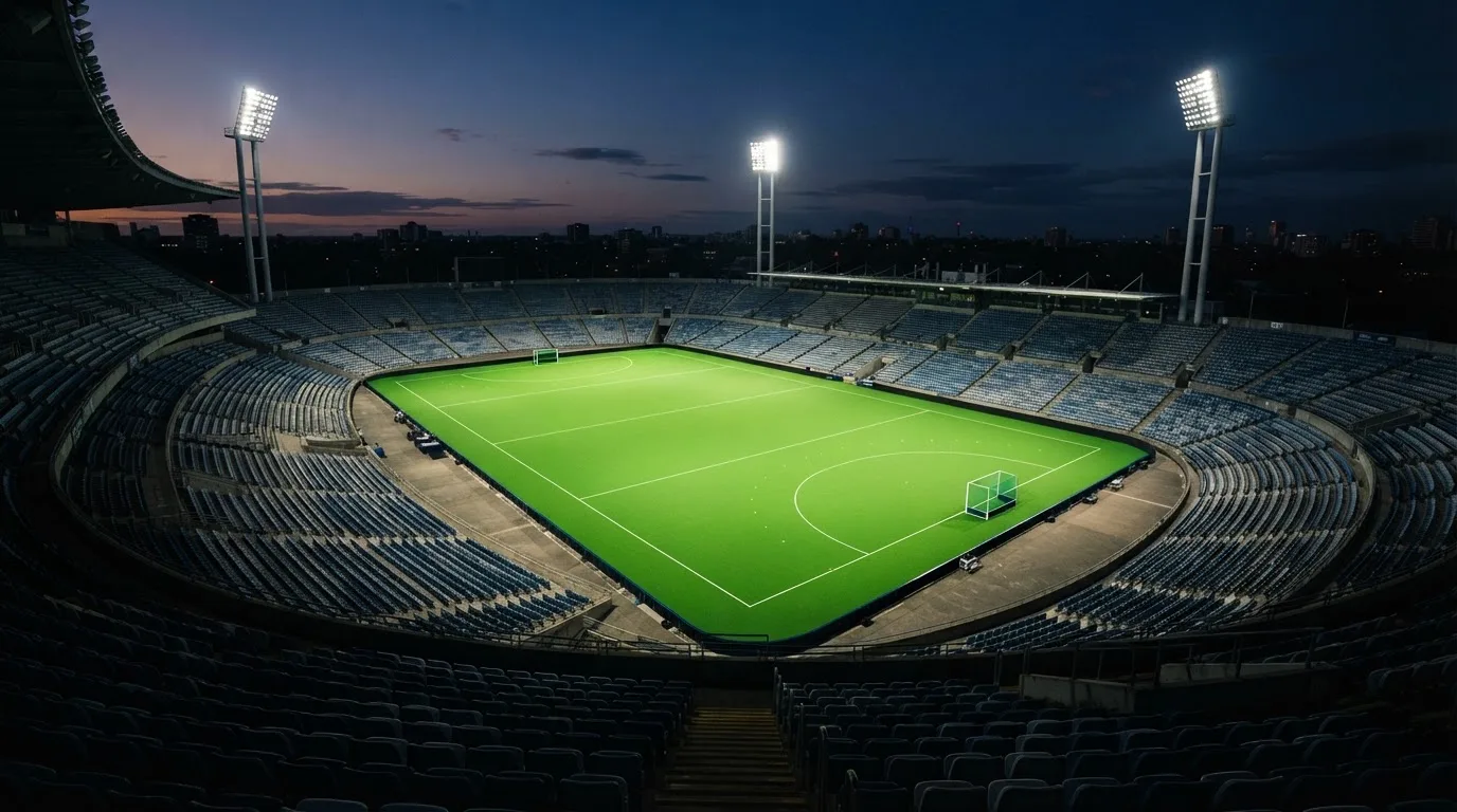 An empty football stadium with floodlight masts at dusk