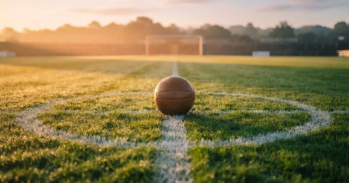 A ball on the centre spot of a grass pitch in morning light
