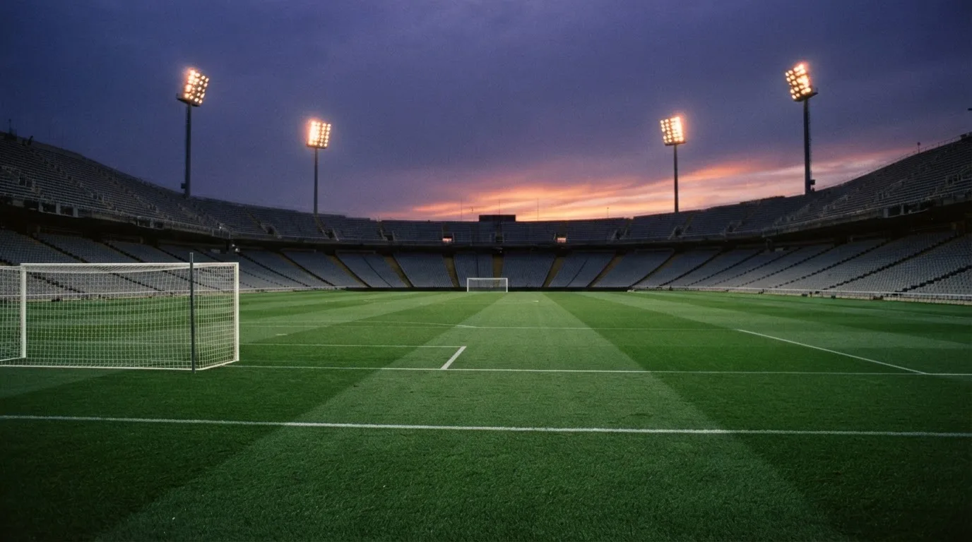 An empty football stadium with floodlight masts at dusk