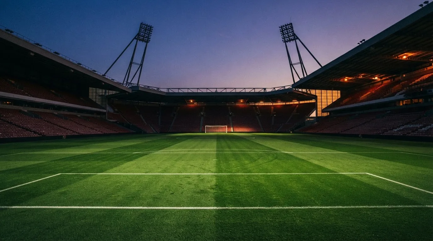 An empty football stadium with floodlight masts at dusk