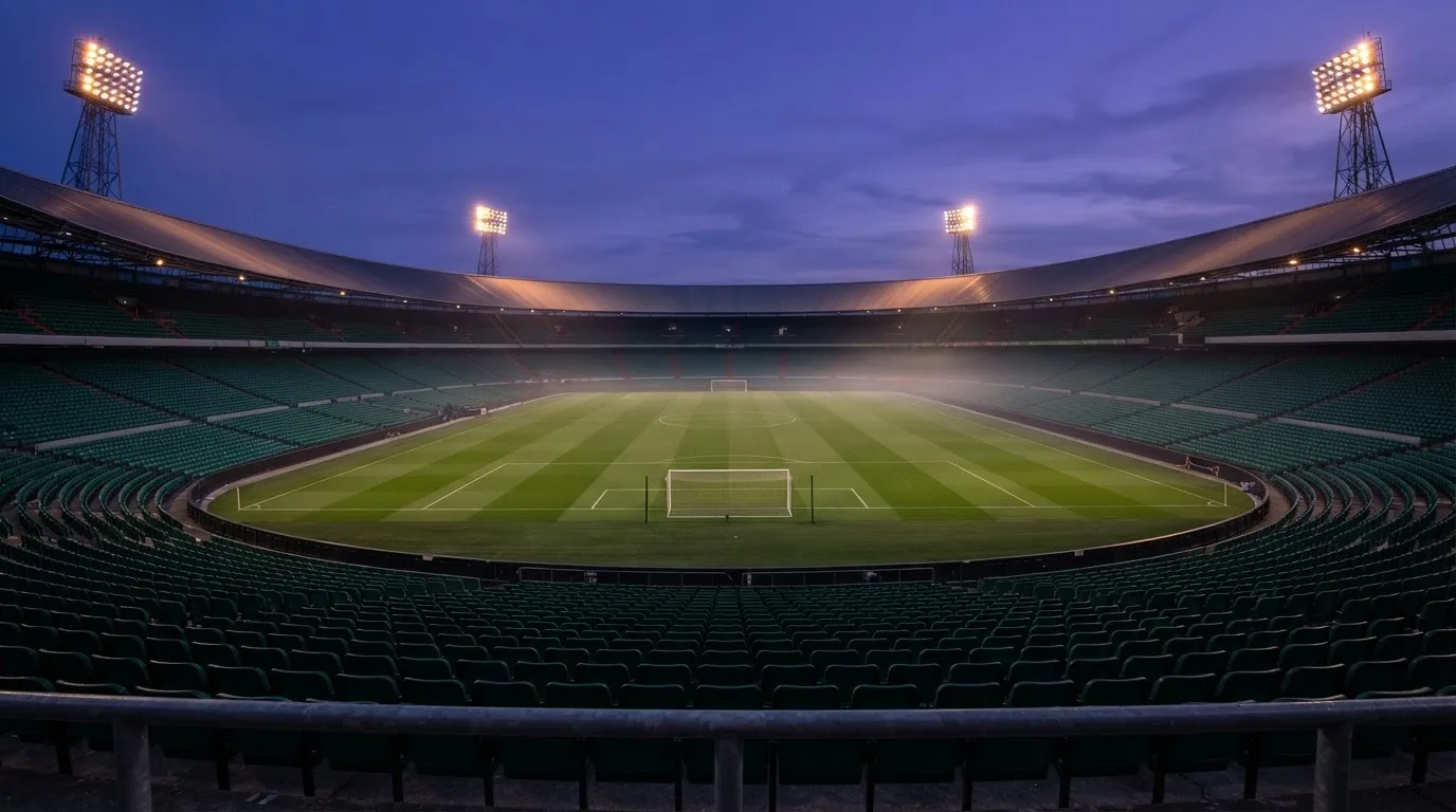 An empty football stadium with floodlight masts at dusk
