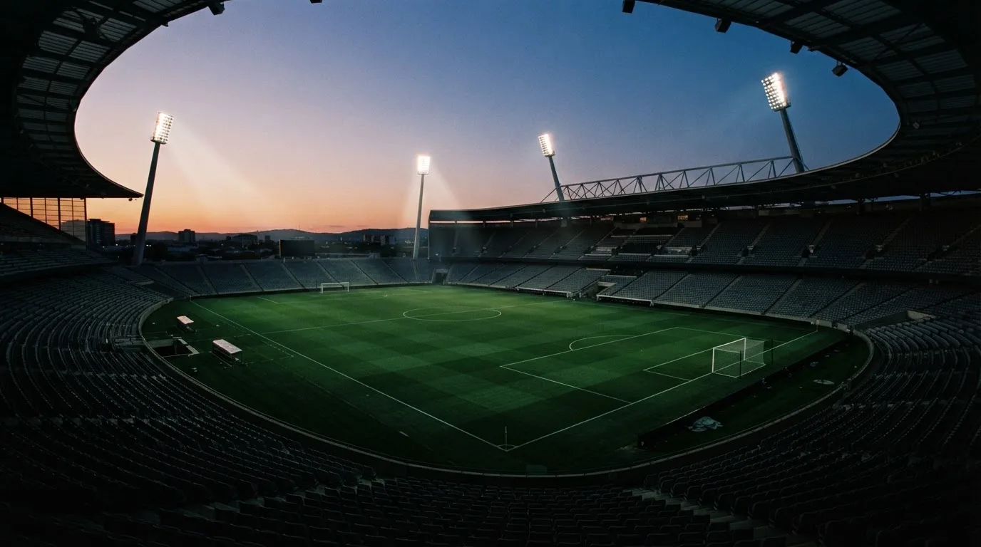 An empty football stadium with floodlight masts at dusk