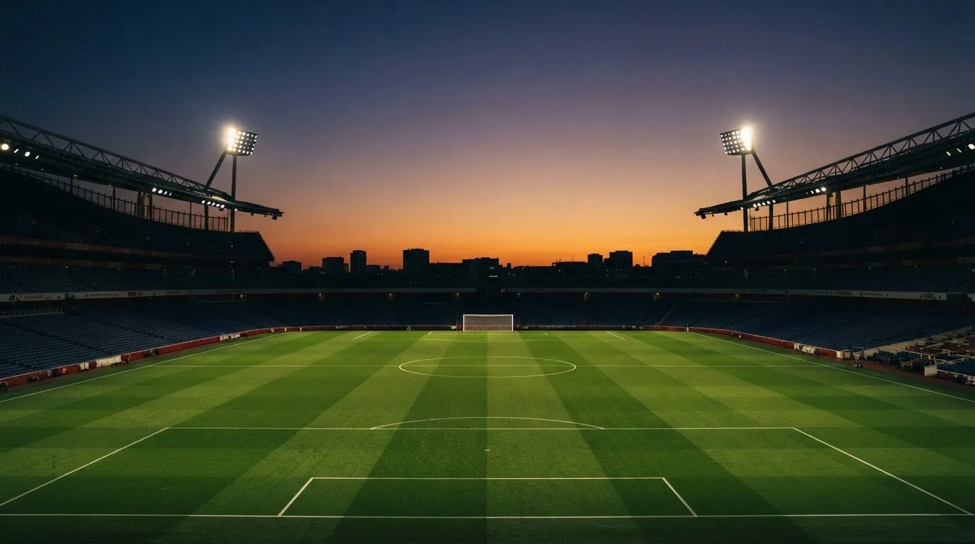 An empty football stadium with floodlight masts at dusk