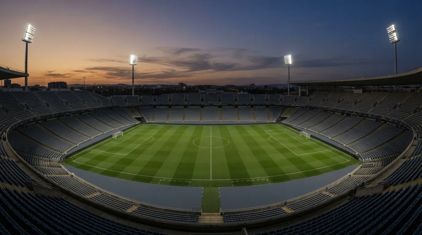 An empty football stadium with floodlight masts at dusk