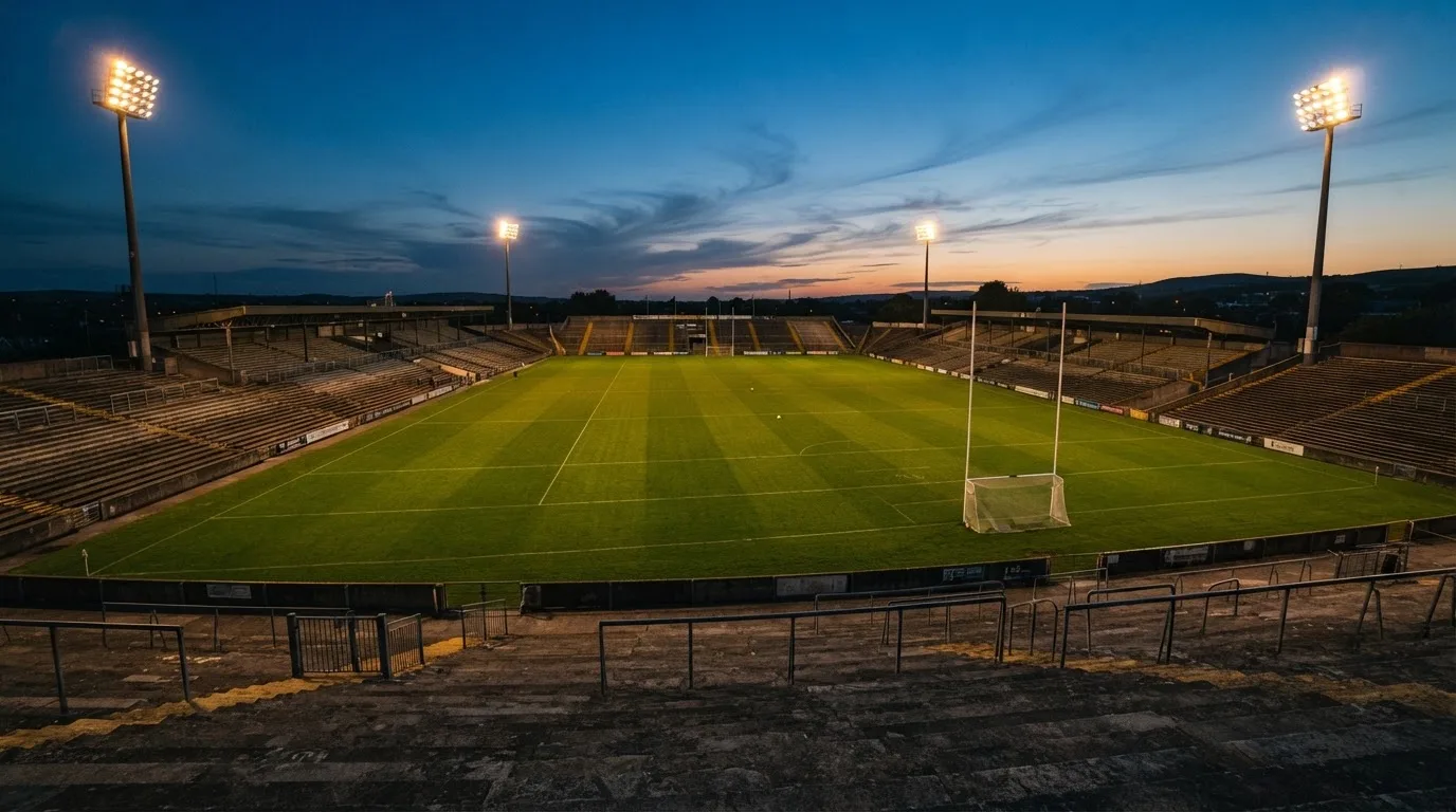 An empty football stadium with floodlight masts at dusk