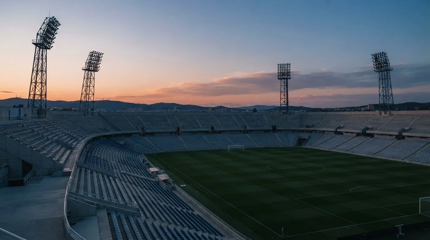 An empty football stadium with floodlight masts at dusk