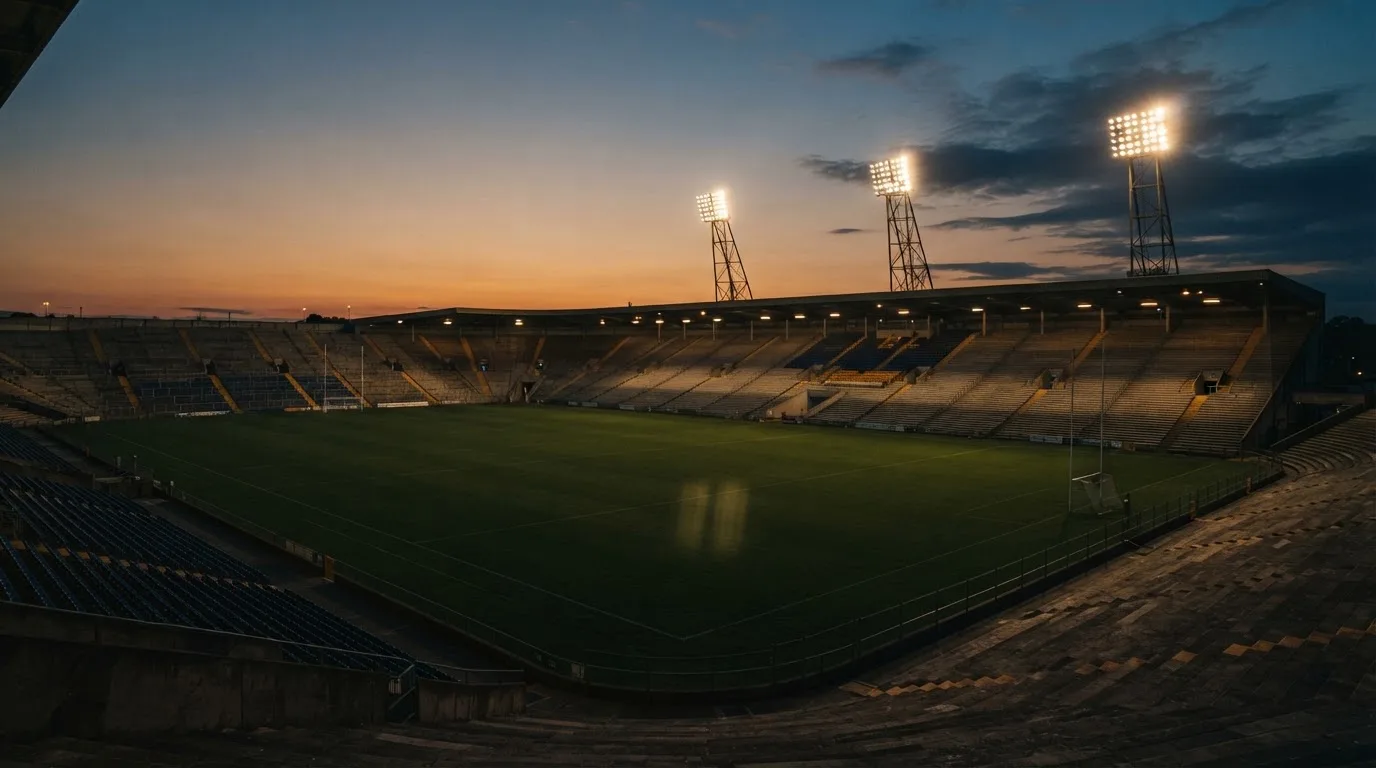 An empty football stadium with floodlight masts at dusk