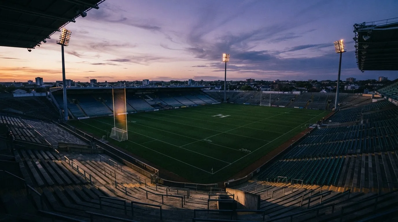 An empty football stadium with floodlight masts at dusk