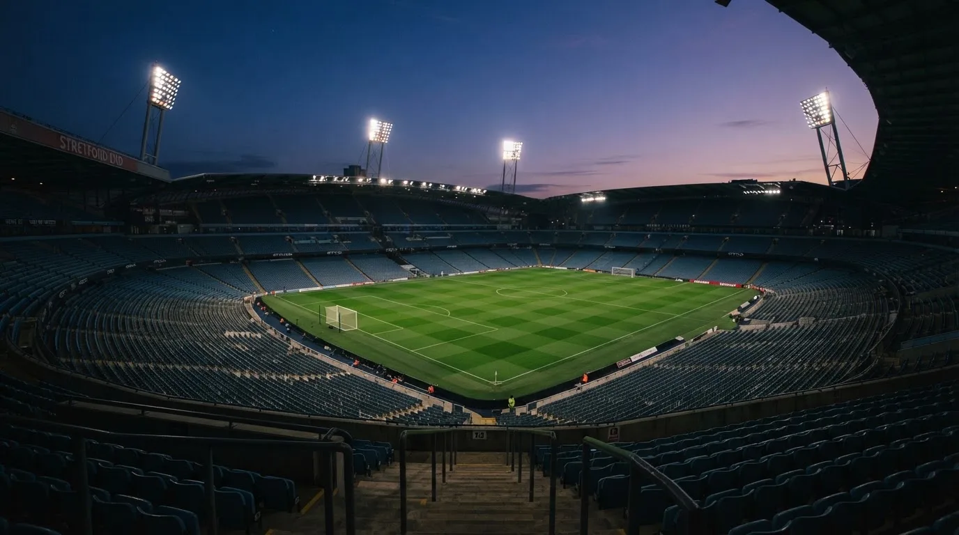 An empty football stadium with floodlight masts at dusk