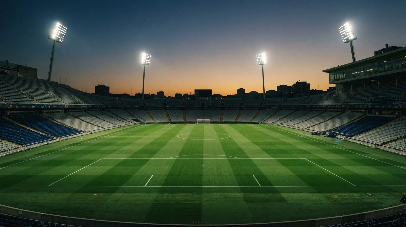 An empty football stadium with floodlight masts at dusk