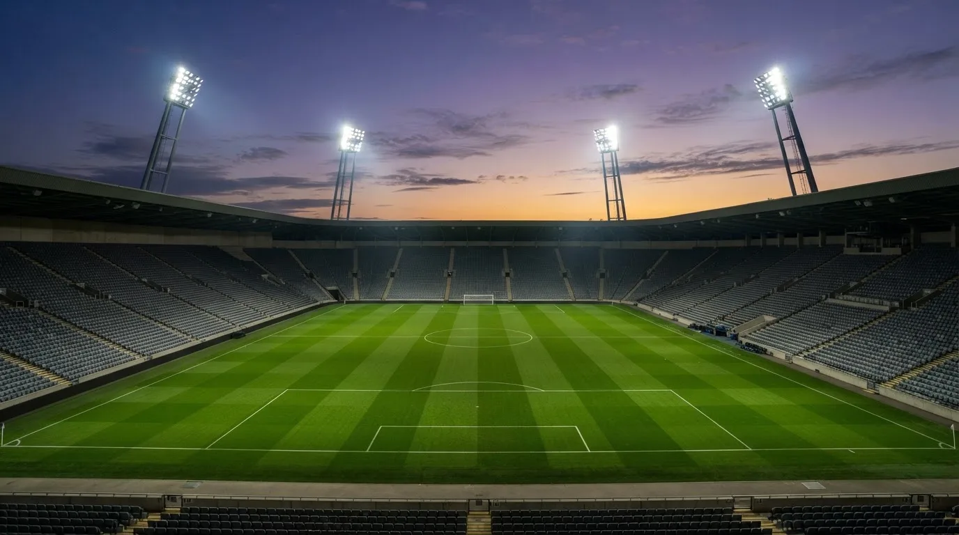 An empty football stadium with floodlight masts at dusk
