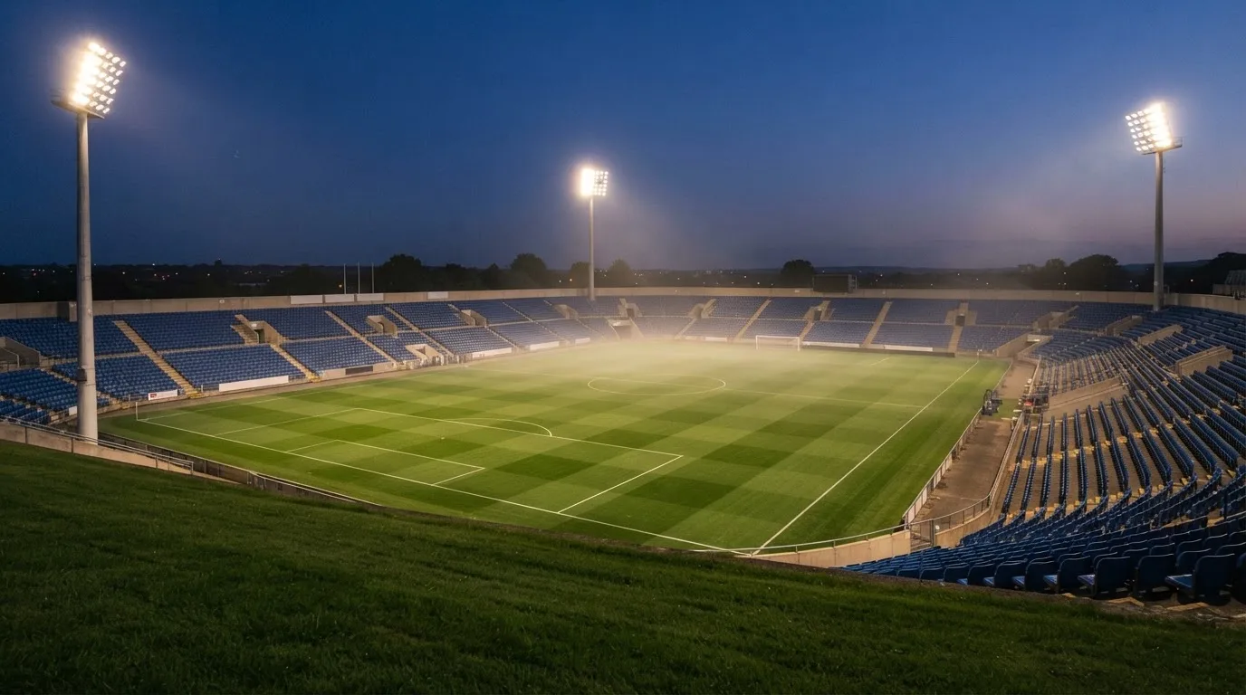 An empty football stadium with floodlight masts at dusk