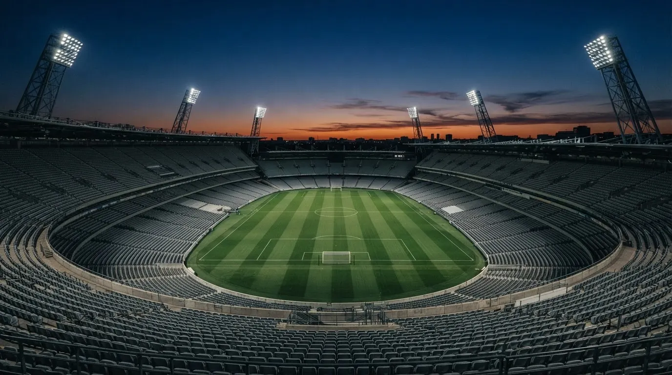 An empty football stadium with floodlight masts at dusk