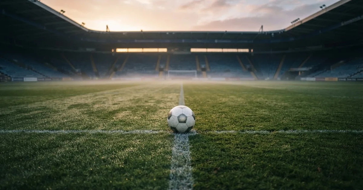 A ball on the centre spot of a grass pitch in morning light