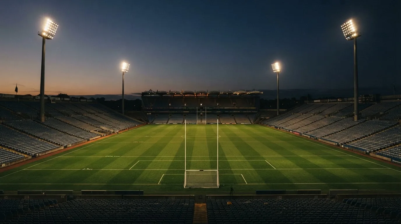 An empty football stadium with floodlight masts at dusk