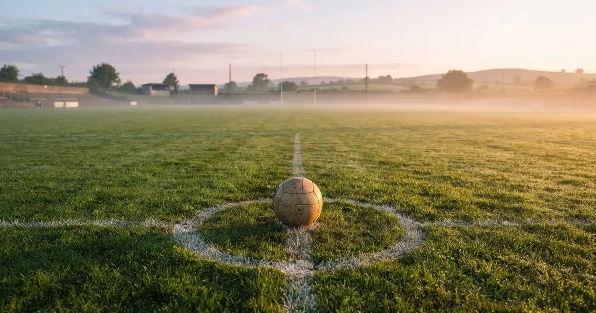 A ball on the centre spot of a grass pitch in morning light