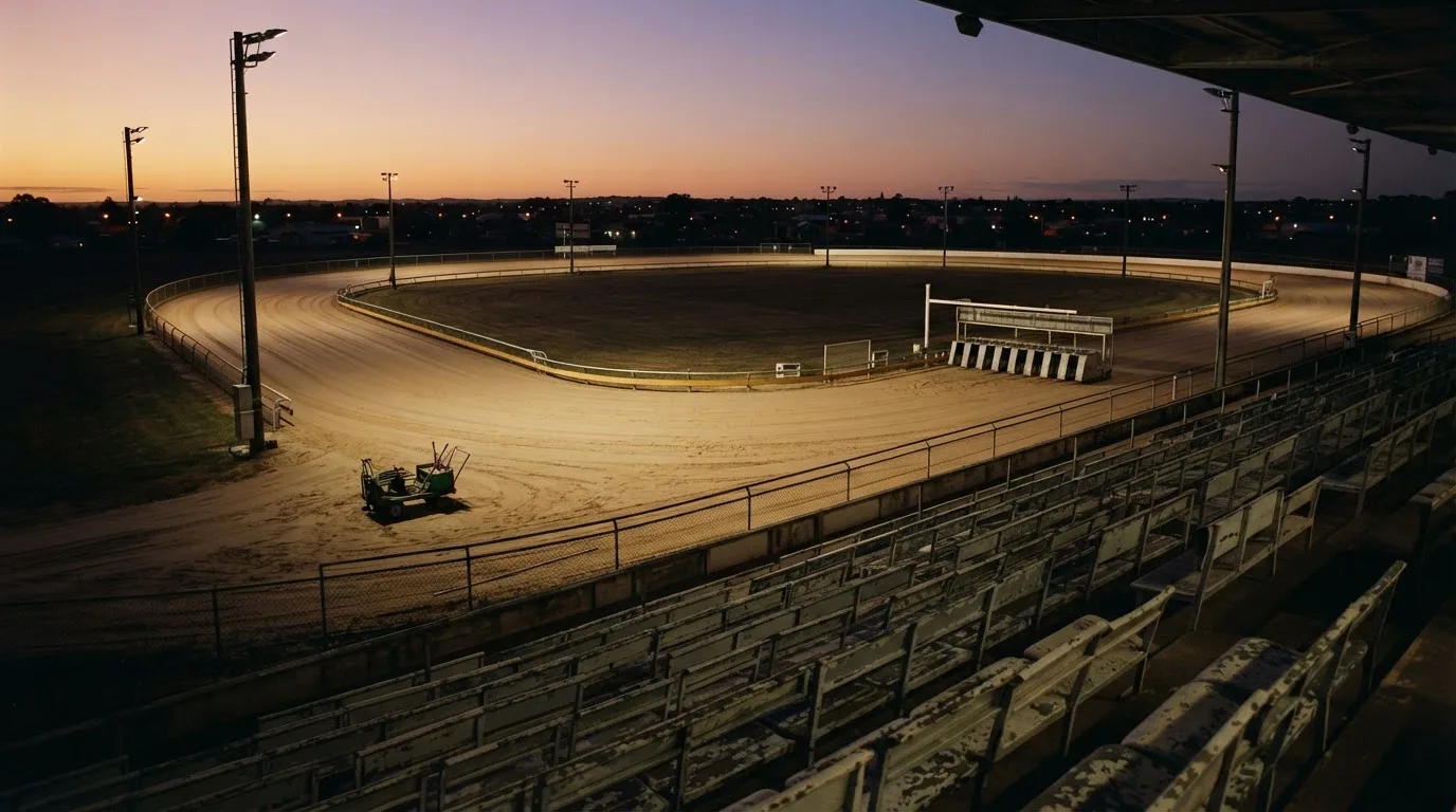 An empty football stadium with floodlight masts at dusk