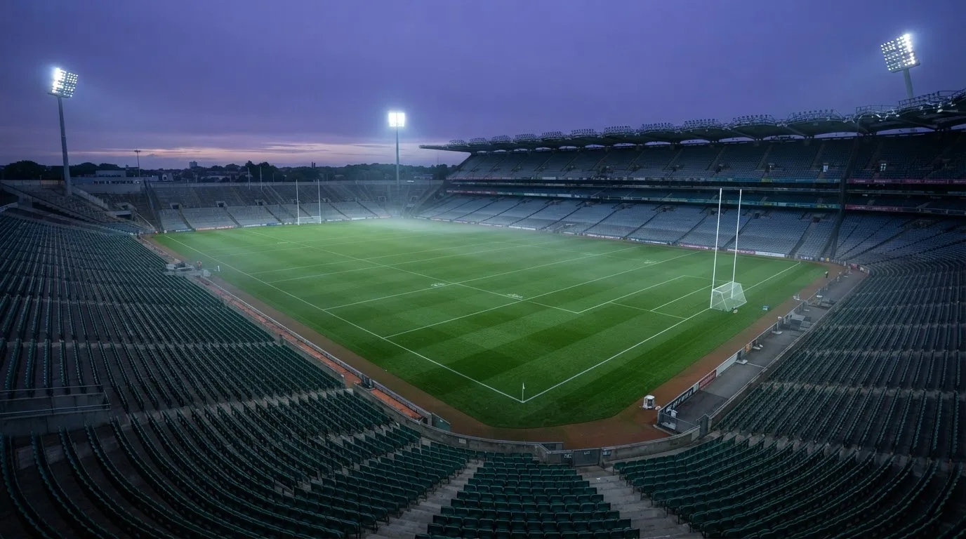 An empty football stadium with floodlight masts at dusk