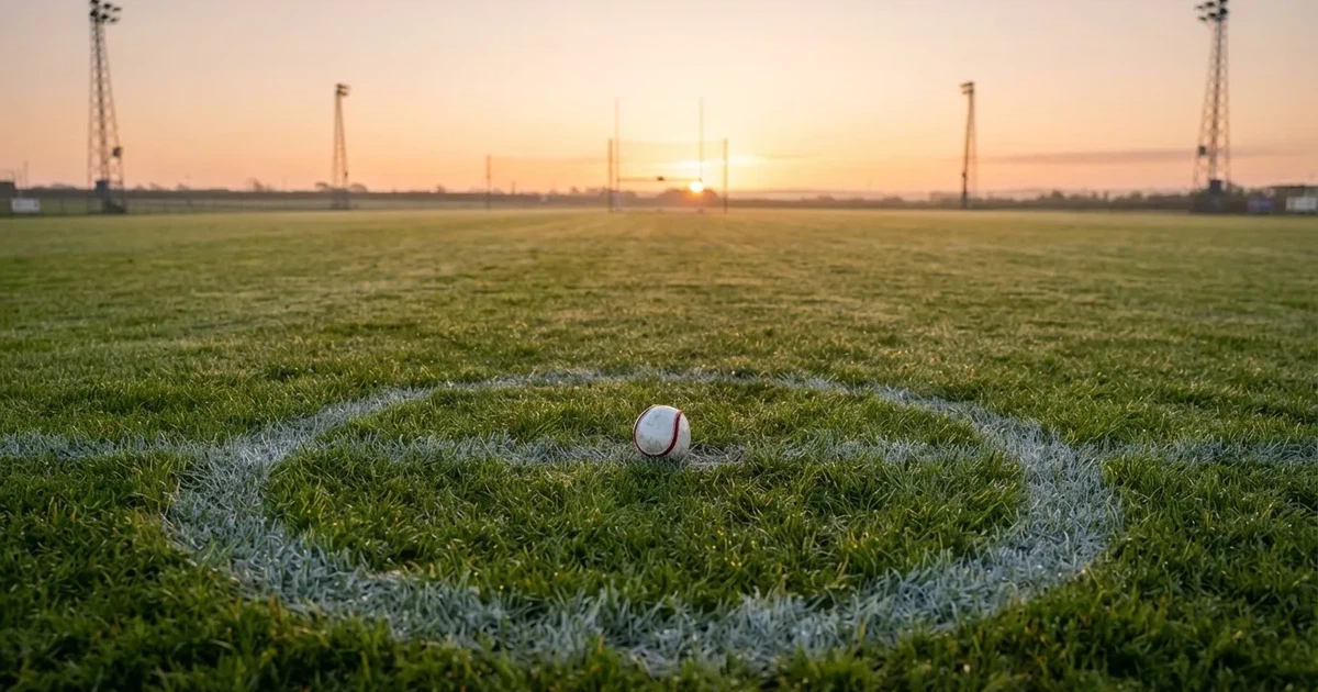 A ball on the centre spot of a grass pitch in morning light