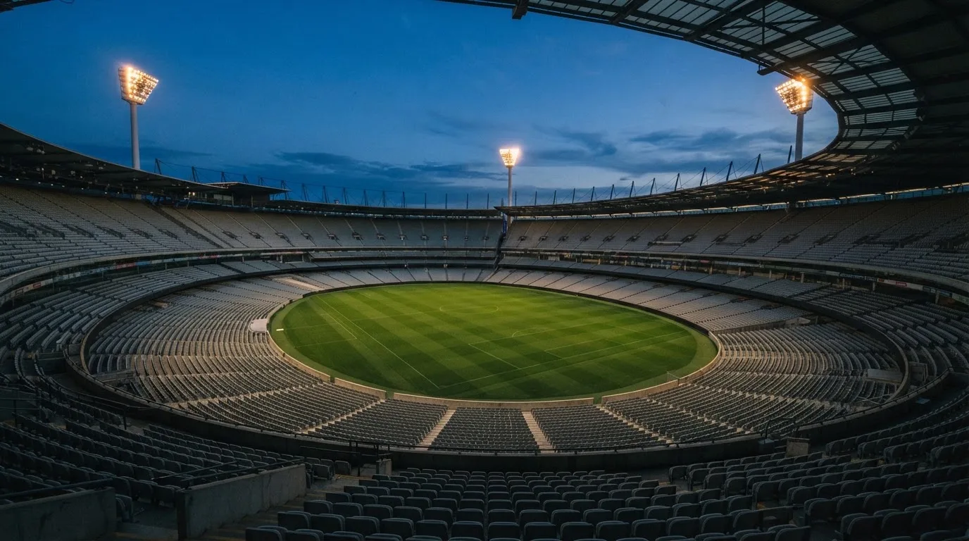 An empty football stadium with floodlight masts at dusk