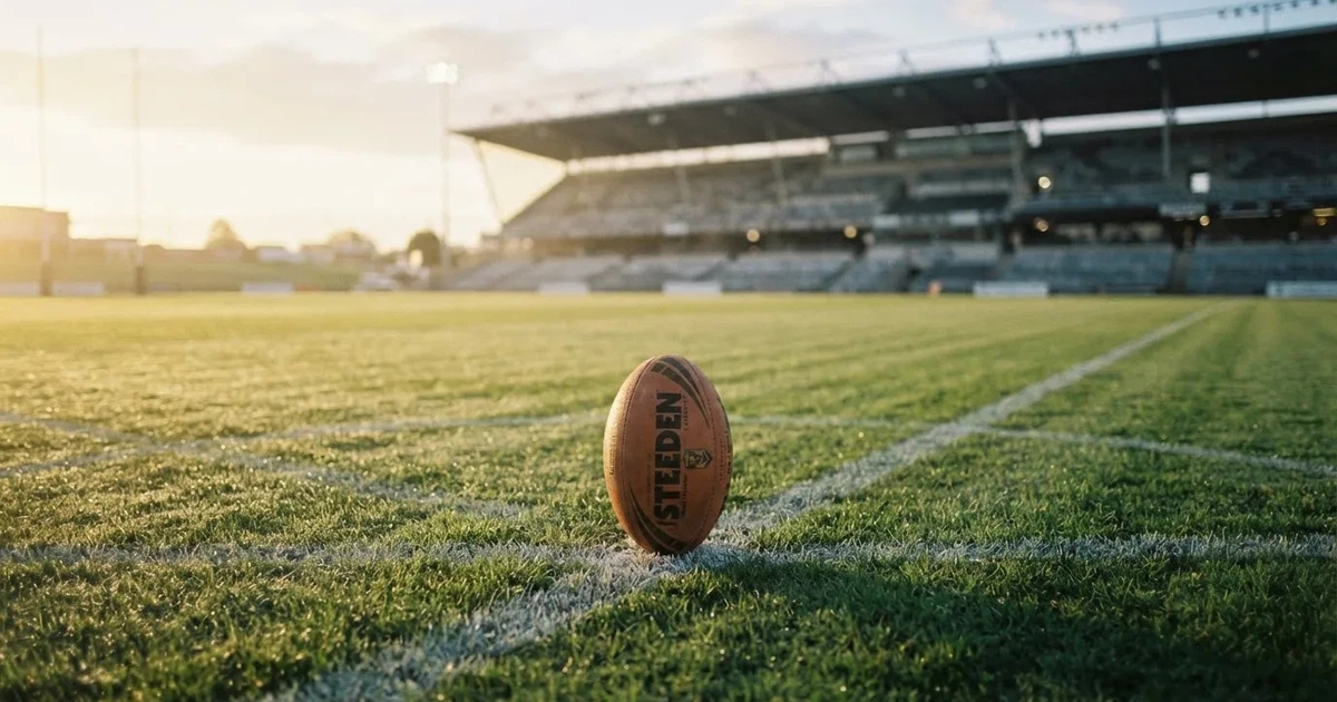 A ball on the centre spot of a grass pitch in morning light