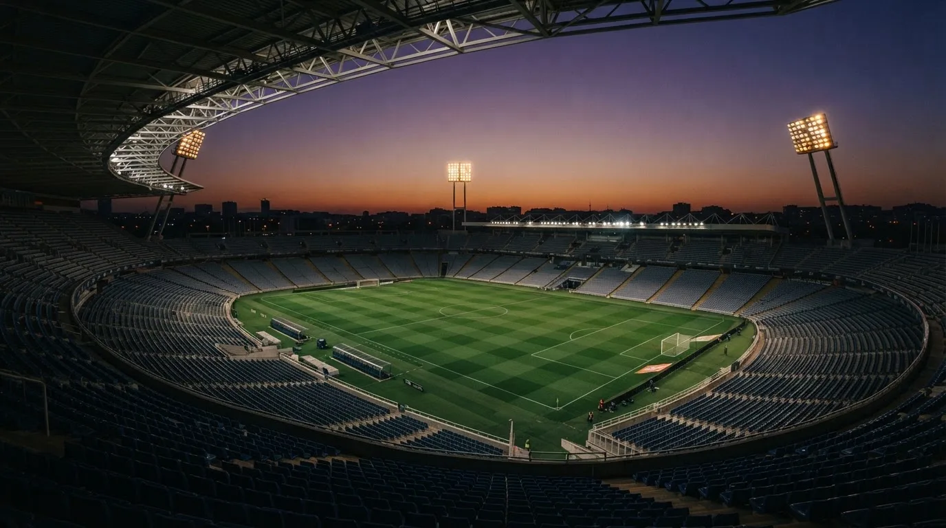 An empty football stadium with floodlight masts at dusk