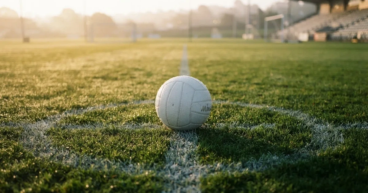 A ball on the centre spot of a grass pitch in morning light