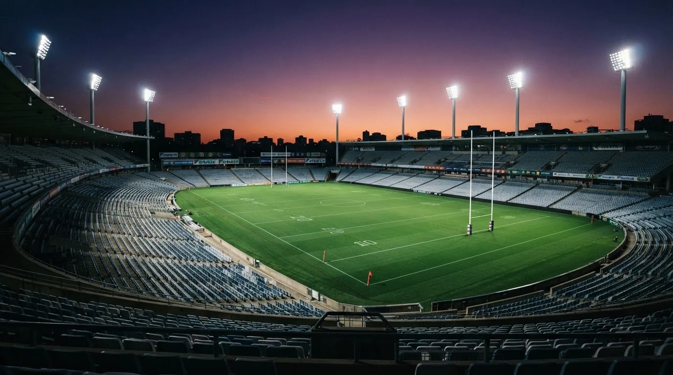 An empty football stadium with floodlight masts at dusk